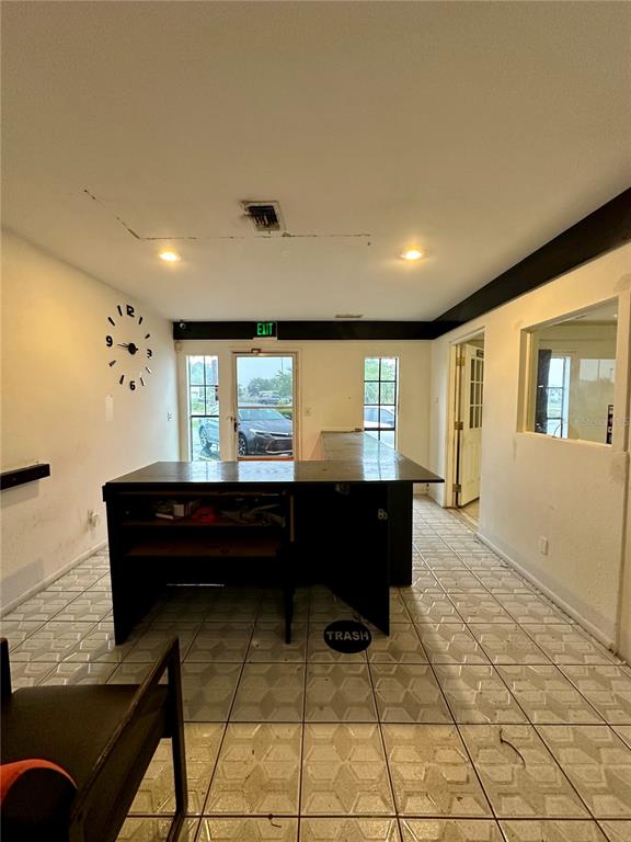 A room with a dark service counter, tile flooring, a wall clock, and an exit door — 1210-1232 DYER BOULEVARD UNIT 1218, KISSIMMEE, FL