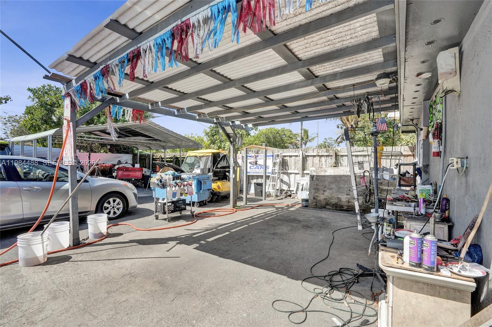 An outdoor covered workspace features a concrete floor, a silver car, and various tools — 345 COPANS RD, Pompano Beach FL 33064, POMPANO BEACH, FL