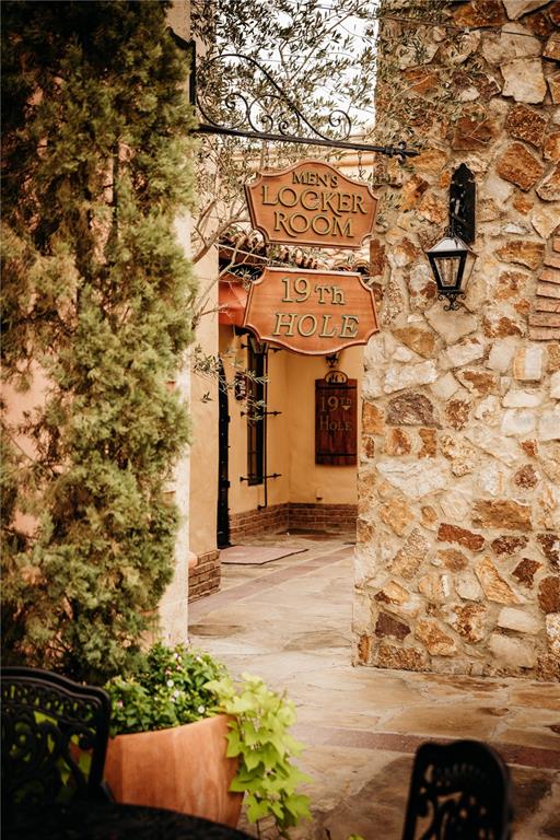 A stone-walled walkway features hanging wooden signs for a men's locker room and 19th hole — 15414 APENNINE WAY, MONTVERDE, FL