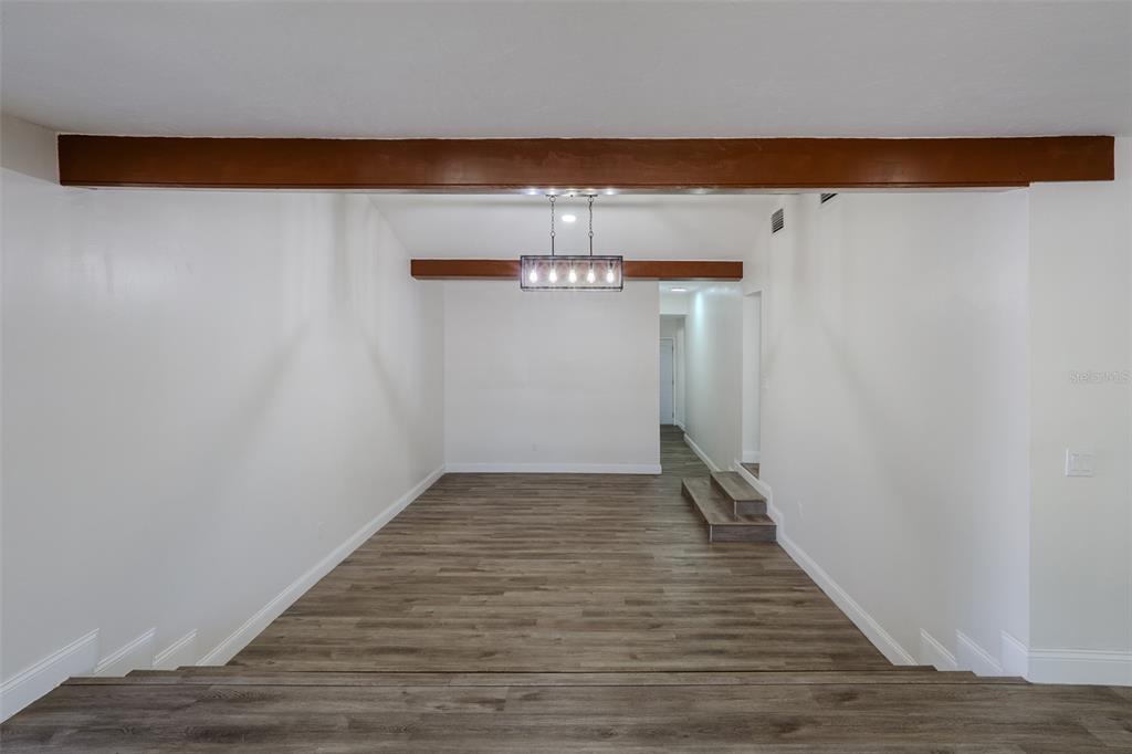 A sunken living area features wood-look flooring, white walls, and exposed wooden ceiling beams — 599 CAROLINA AVENUE, FORT MYERS, FL