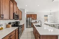 A kitchen features wood cabinets, white countertops, a large island, and stainless steel appliances — 5277 ROYAL POINT AVENUE, KISSIMMEE, FL