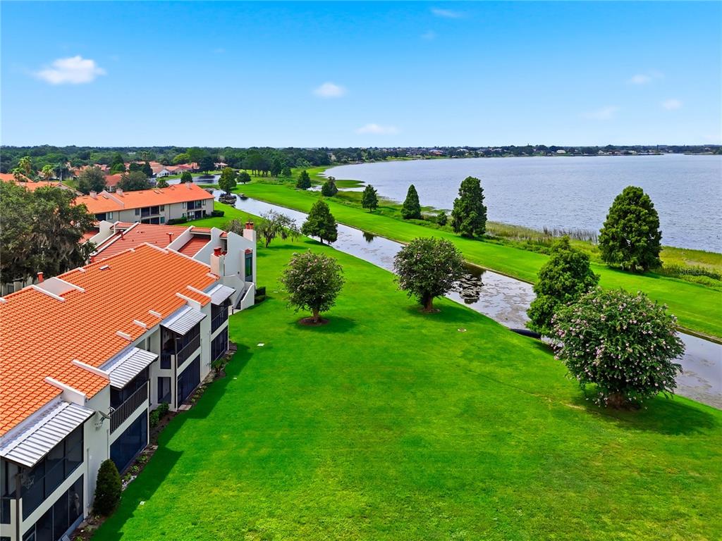 An aerial view shows a multi-story apartment building beside a grassy lawn and a canal — 503 SWEET BAY CIRCLE, WINTER HAVEN, FL