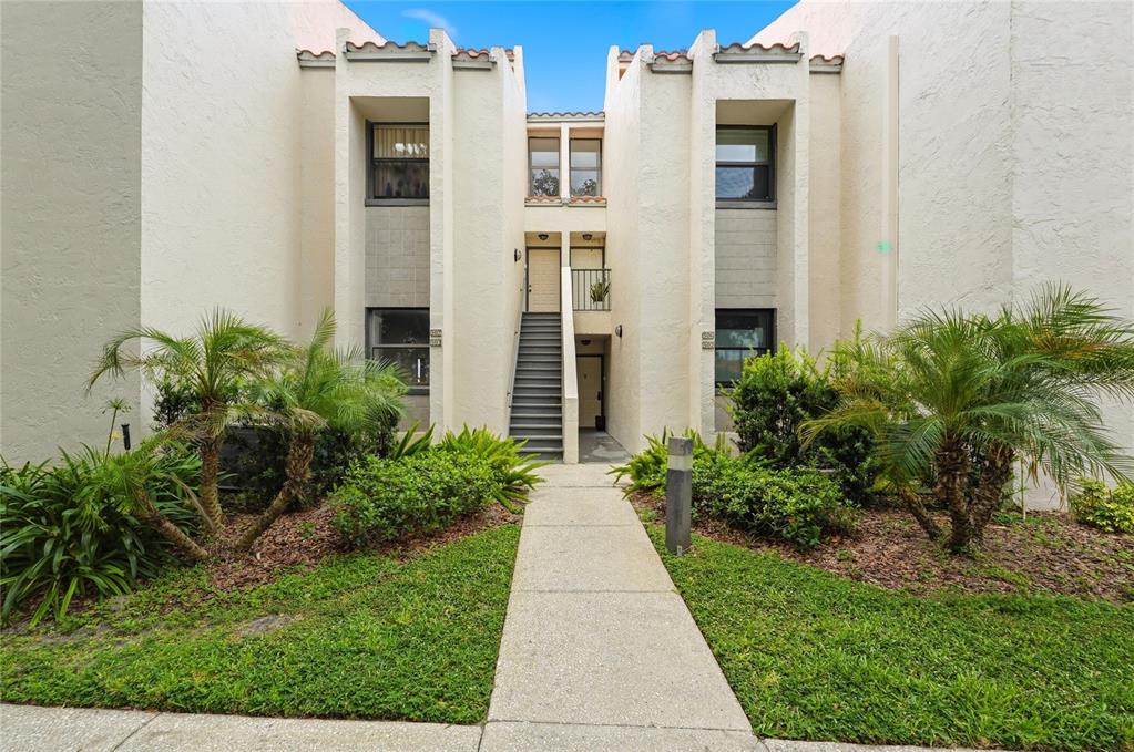 A concrete walkway leads to the exterior staircase of a two-story apartment building — 503 SWEET BAY CIRCLE, WINTER HAVEN, FL