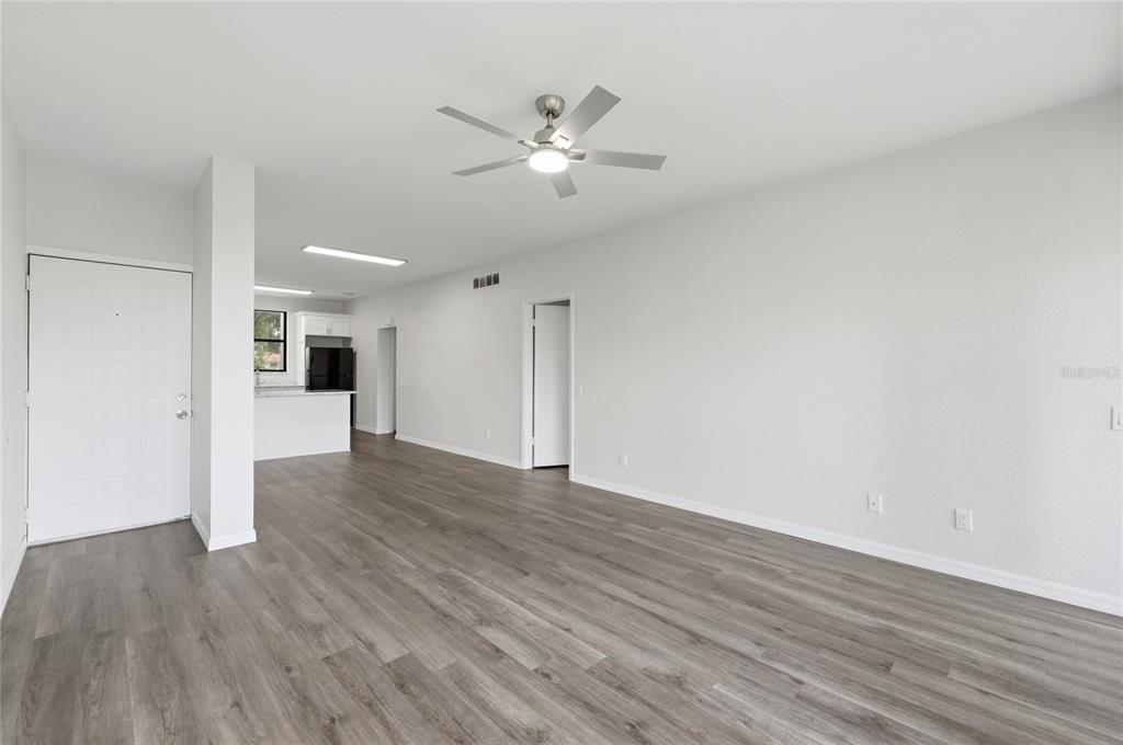 An open-concept living area features gray wood-look flooring, white walls, and a ceiling fan — 503 SWEET BAY CIRCLE, WINTER HAVEN, FL