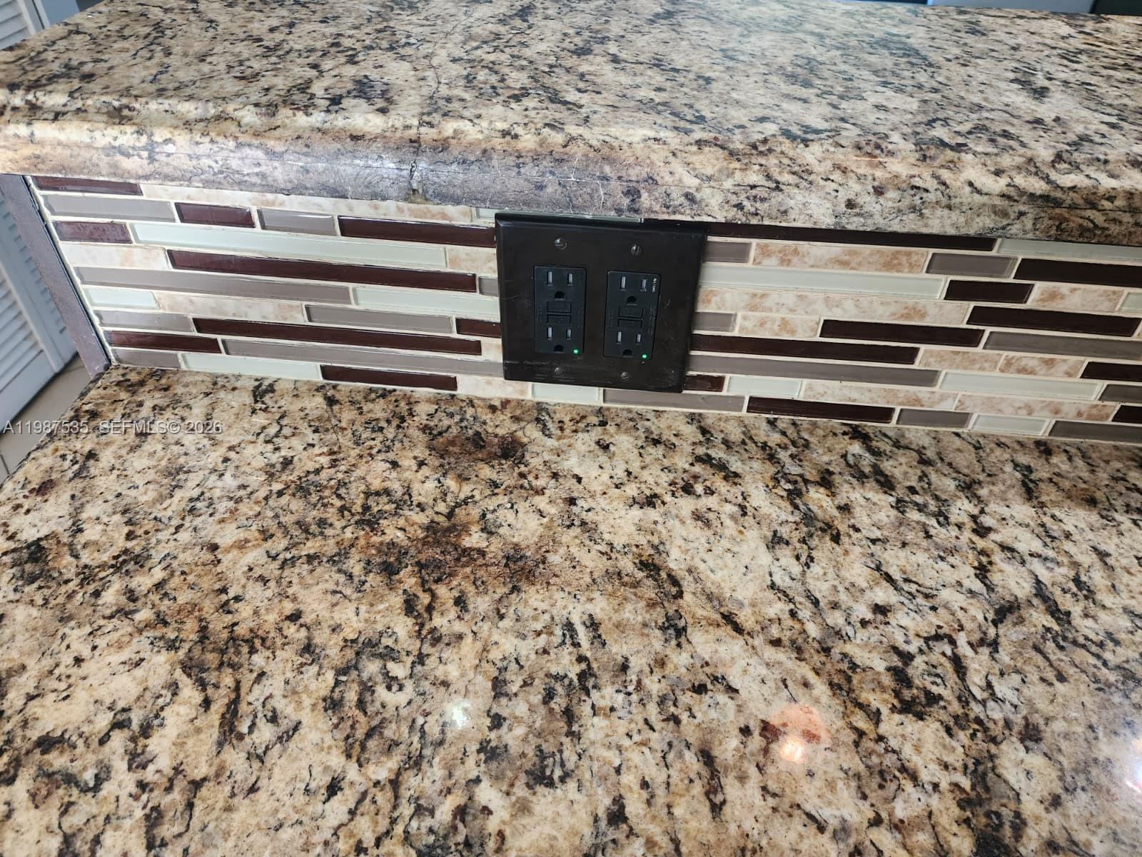 A close-up view shows a granite countertop with a tiled backsplash and a black electrical outlet — 537 N University Dr # 71, Plantation FL 33324, PLANTATION, FL