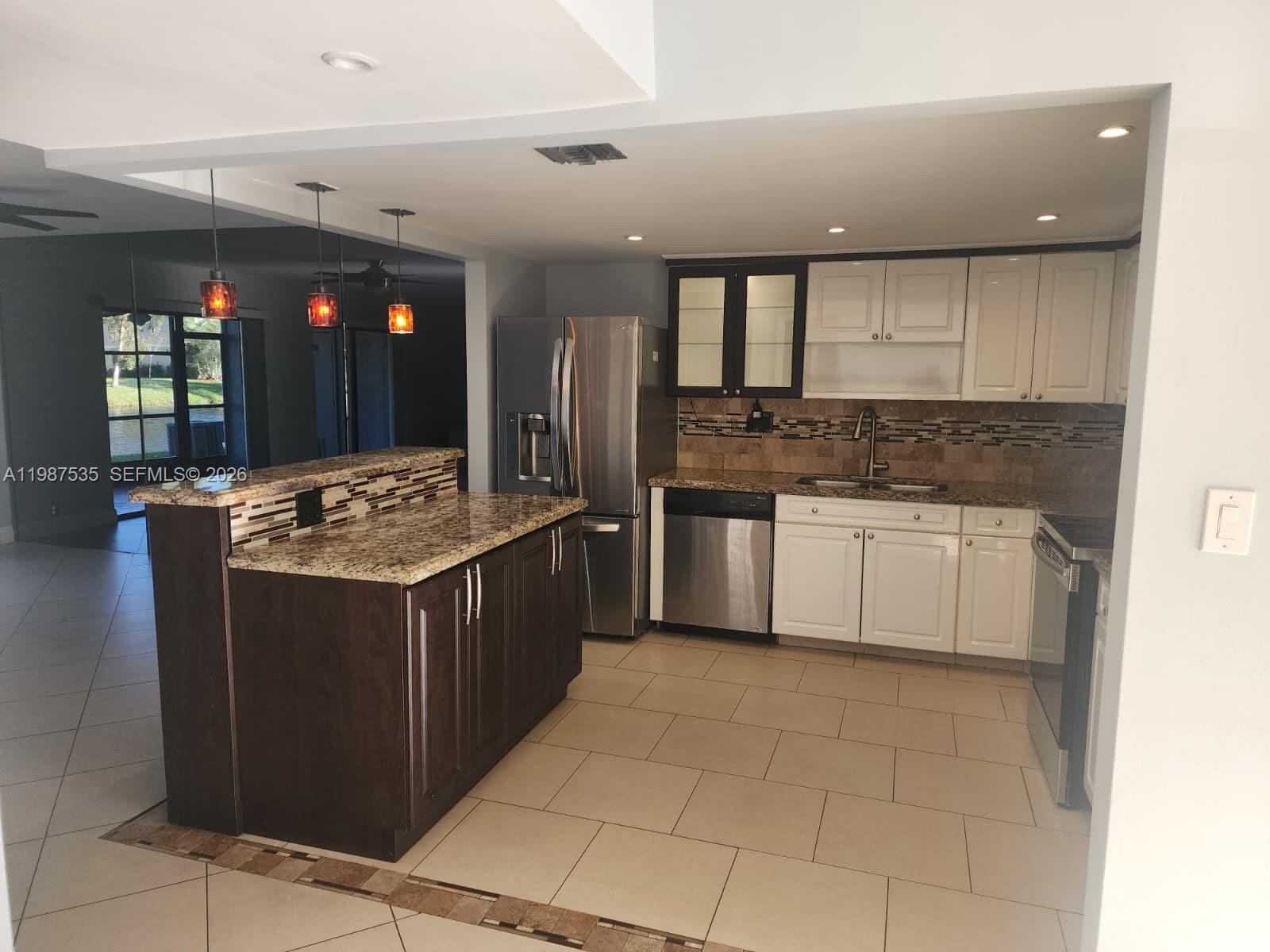 A kitchen features dark wood cabinets, white cabinetry, granite countertops, and stainless steel appliances — 537 N University Dr # 71, Plantation FL 33324, PLANTATION, FL