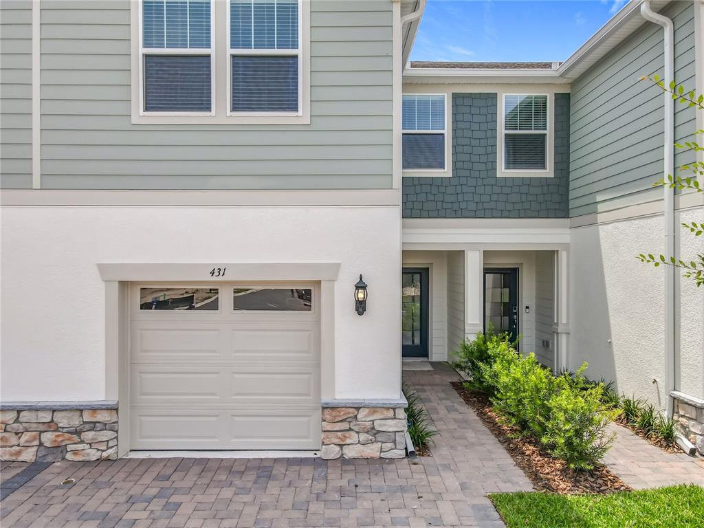 A two-story townhouse exterior features a garage, stone accents, and a paved walkway — 431 MEADOWLAND POINT, OVIEDO, FL