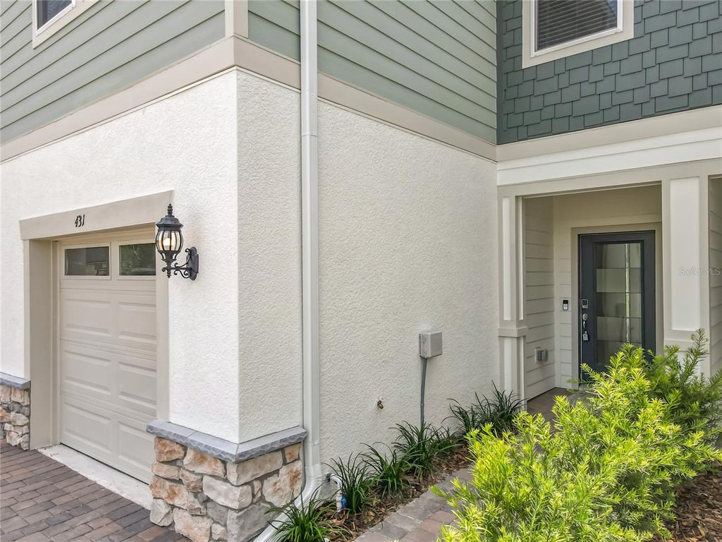 Exterior view of a home entrance featuring a garage, stucco walls, and stone accents — 431 MEADOWLAND POINT, OVIEDO, FL