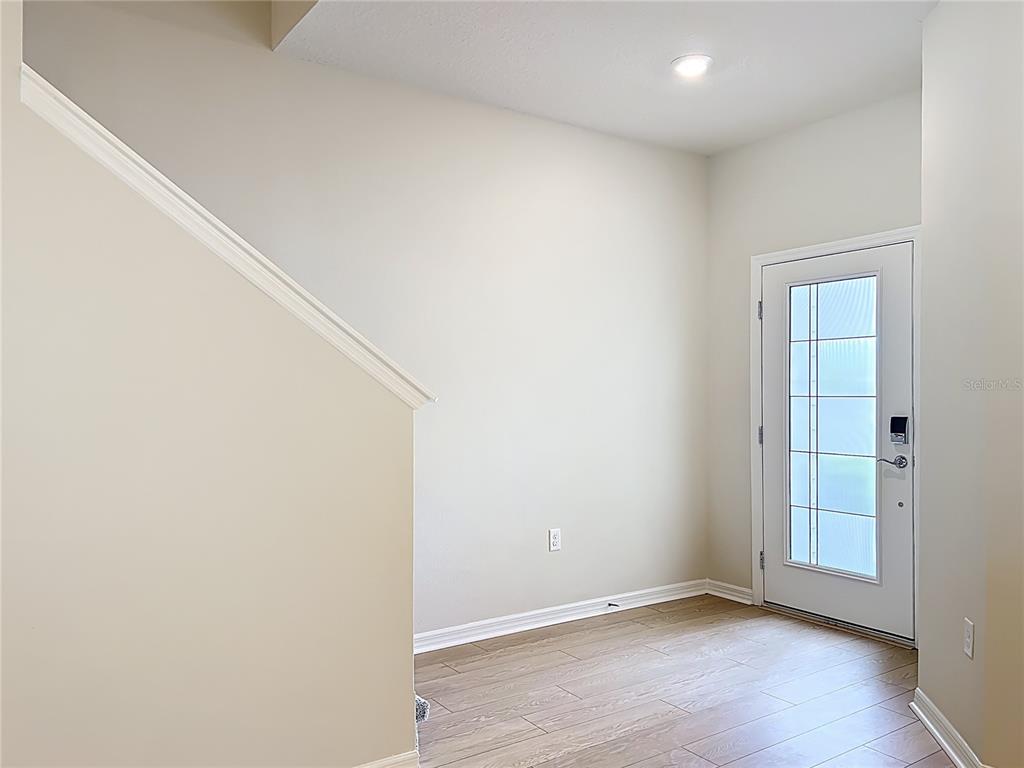 An entryway features light wood-look flooring, beige walls, a staircase, and a glass-paneled front door — 431 MEADOWLAND POINT, OVIEDO, FL