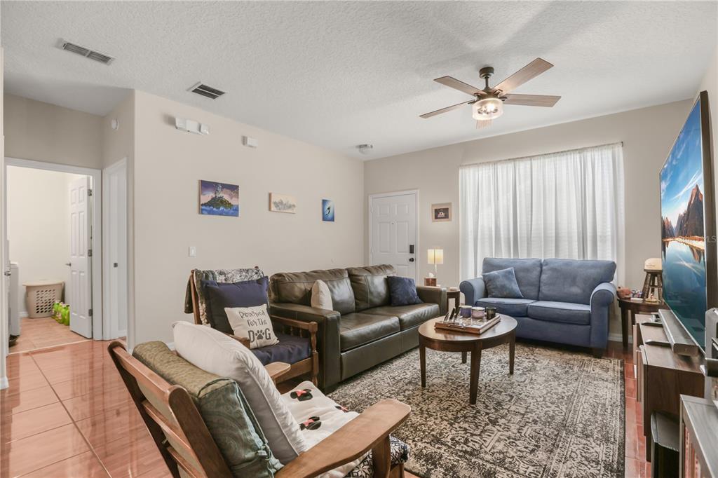 A living room features a brown leather sofa, a blue loveseat, and a wooden armchair — 3141 SUN LAKE COURT UNIT A, KISSIMMEE, FL