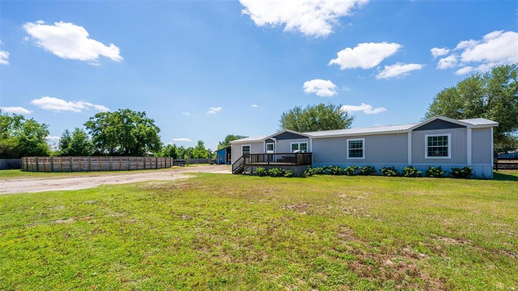 A single-story manufactured home with a wooden deck sits on a large grassy lot — 18350 SE 42ND PLACE, MORRISTON, FL
