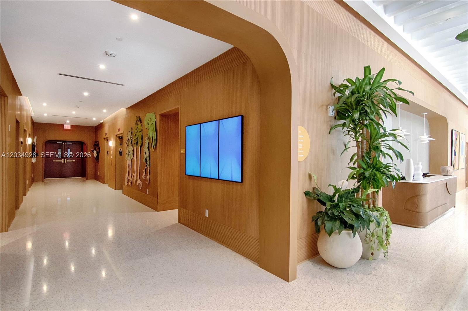 A modern lobby features wood-paneled walls, a digital display, and a large potted plant — 90 NE 32 # 520, Miami FL 33127, MIAMI, FL