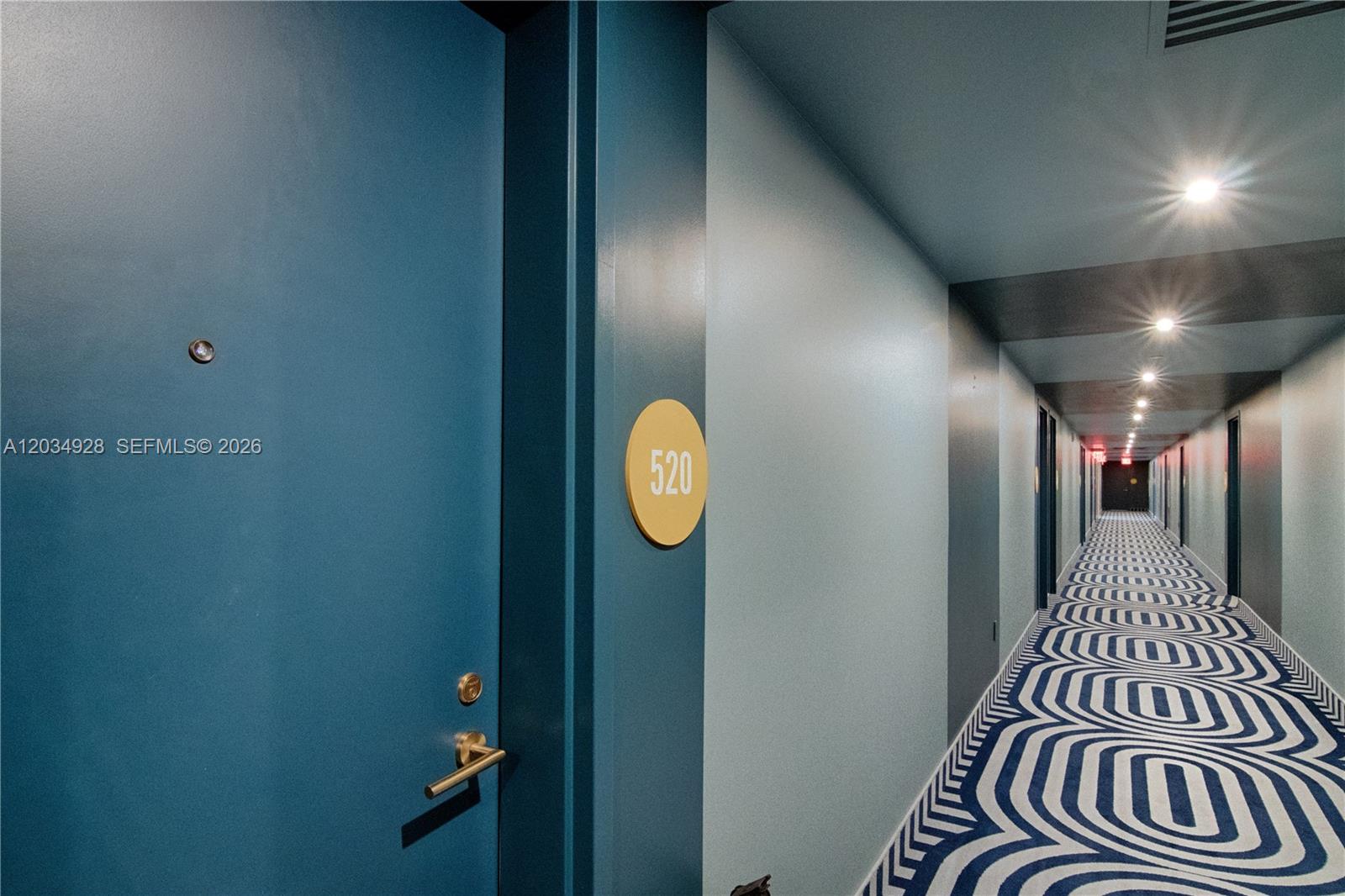 A blue door with a room number sign leads into a hallway with patterned carpet — 90 NE 32 # 520, Miami FL 33127, MIAMI, FL