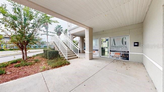 An exterior view of a commercial building entrance with a concrete walkway and metal stairs — 160 CYPRESS POINT PARKWAY UNIT A102, PALM COAST, FL