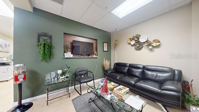 A waiting room features a black leather sofa, a glass coffee table, and green walls — 160 CYPRESS POINT PARKWAY UNIT A102, PALM COAST, FL