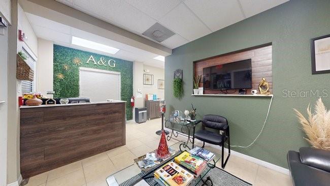 A reception area features a wood-paneled desk, a green accent wall, and a waiting area — 160 CYPRESS POINT PARKWAY UNIT A102, PALM COAST, FL