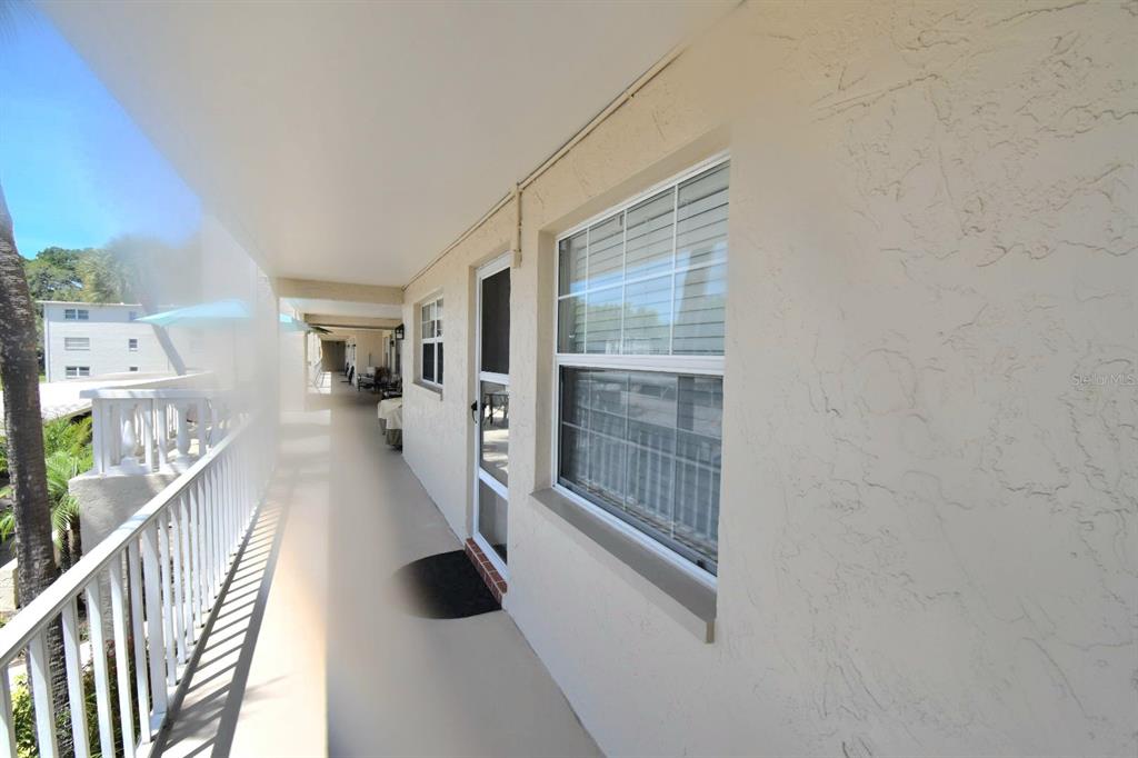 A covered outdoor walkway with a white railing, a window, and a door — 936 VIRGINIA STREET UNIT 206, DUNEDIN, FL