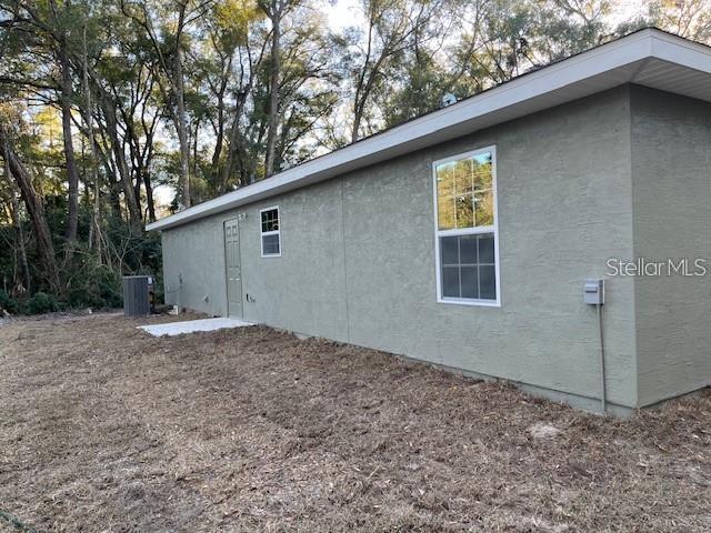 The exterior of a light green stucco house features a single door and one window — 3779 SE 140TH LANE, SUMMERFIELD, FL