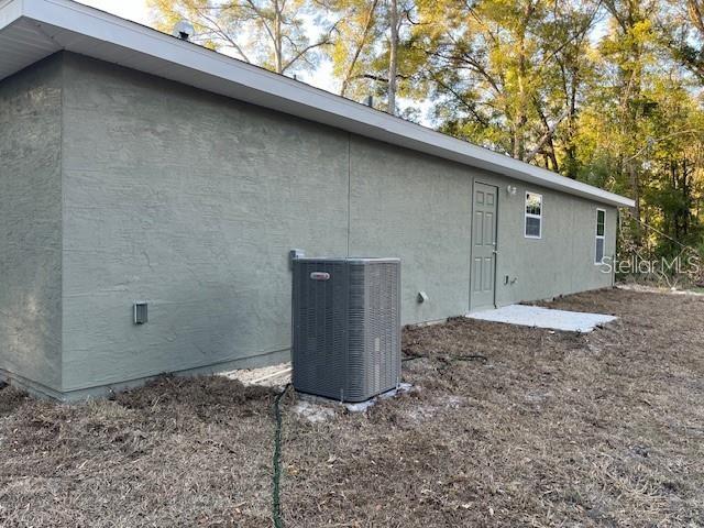 The exterior of a house features stucco siding, an HVAC unit, and a side door — 3779 SE 140TH LANE, SUMMERFIELD, FL