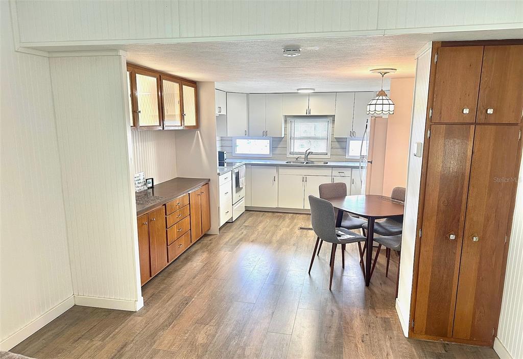 A kitchen features wood-toned lower cabinets, white upper cabinets, and a dining area — 9790 66TH STREET N UNIT 362, PINELLAS PARK, FL