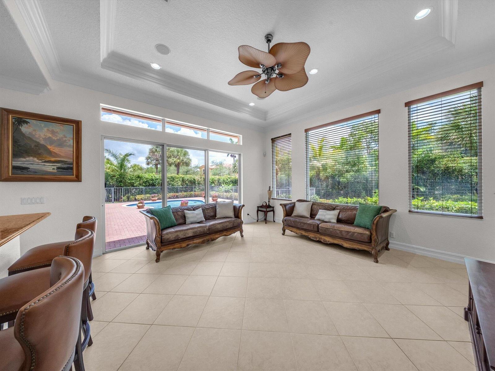 A living room with two leather sofas, tile flooring, and a view of a pool — 7678 NW 117th Lane, Parkland FL 33076, PARKLAND, FL