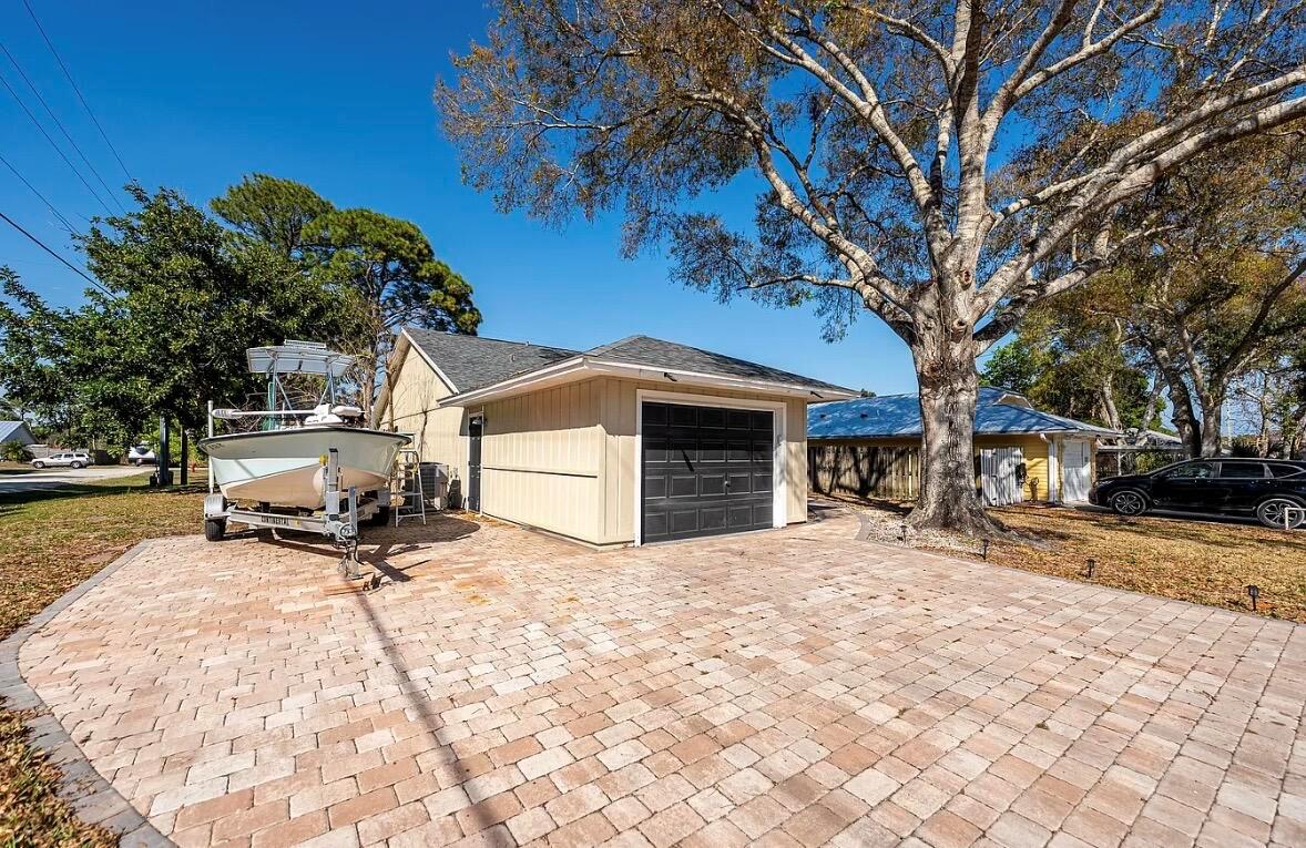 A detached garage with a black door sits on a paved driveway beside a boat — 2890 1st Place, Vero Beach FL 32968, VERO BEACH, FL