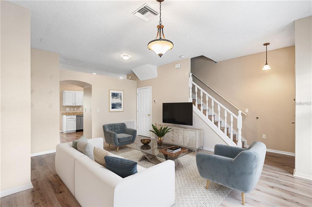 A living room features a white sofa, two armchairs, a television, and a staircase — 10114 FARMINGDALE PLACE, TAMPA, FL