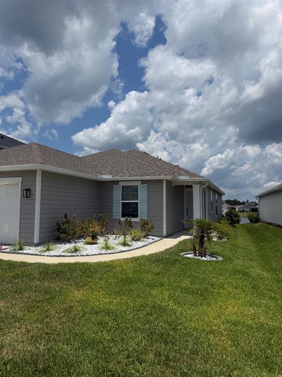 A single-story gray house with light blue shutters, a white garage, and a landscaped yard — 17 WAVERLY LANE, PALM COAST, FL