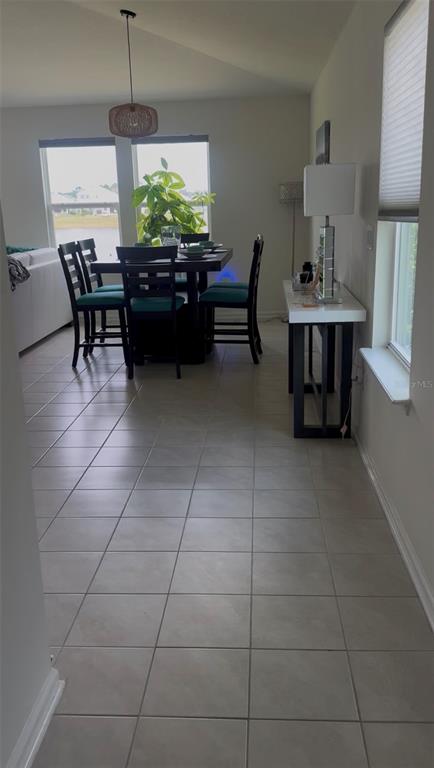 A dining area with a dark table, teal chairs, tile flooring, and a window view — 17 WAVERLY LANE, PALM COAST, FL