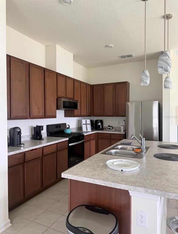 A kitchen features dark wood cabinets, light countertops, stainless steel appliances, and a central island — 17 WAVERLY LANE, PALM COAST, FL