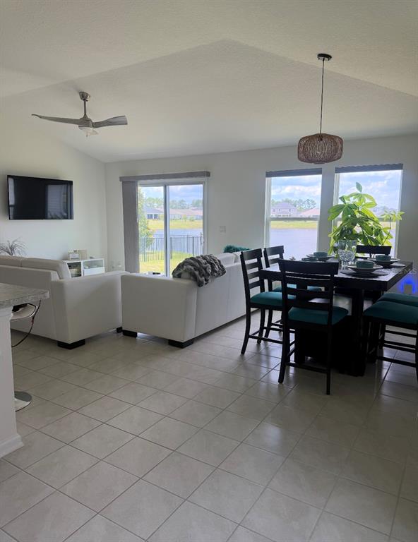 An open-concept living and dining area features tile flooring, white furniture, and a lake view — 17 WAVERLY LANE, PALM COAST, FL