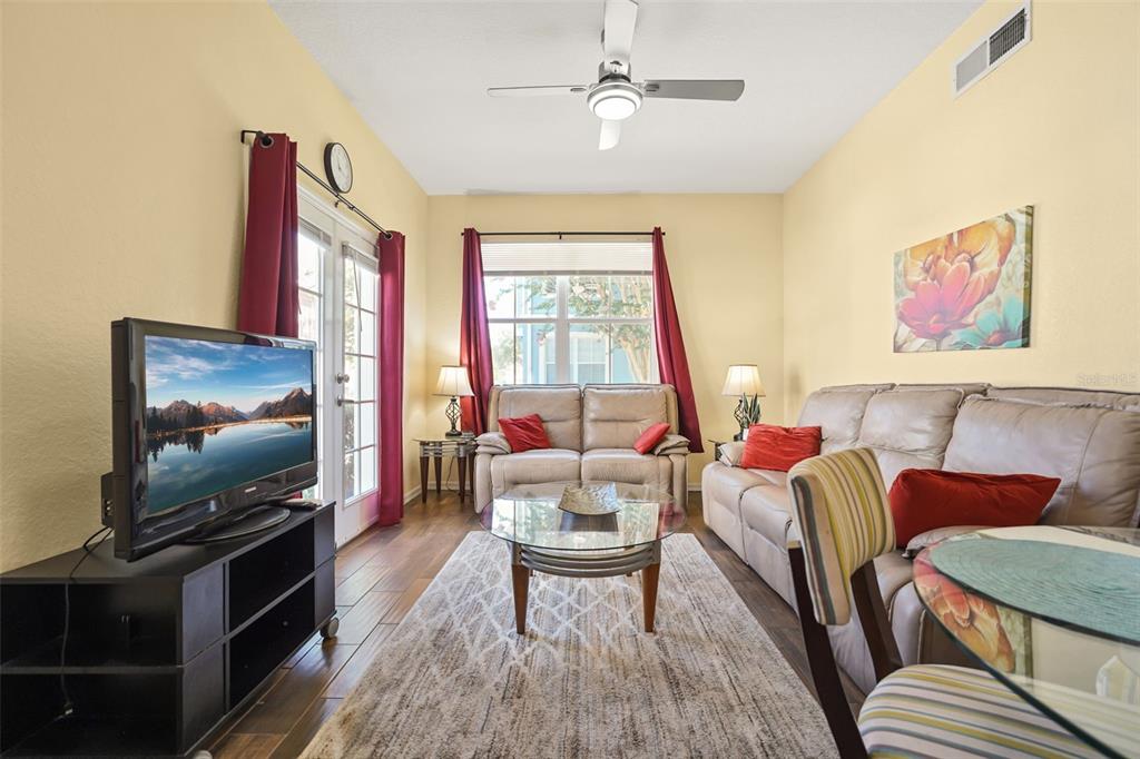 A living room features a television, leather sofas, a glass coffee table, and wood flooring — 4021 VENETIAN BAY DRIVE UNIT 101, KISSIMMEE, FL