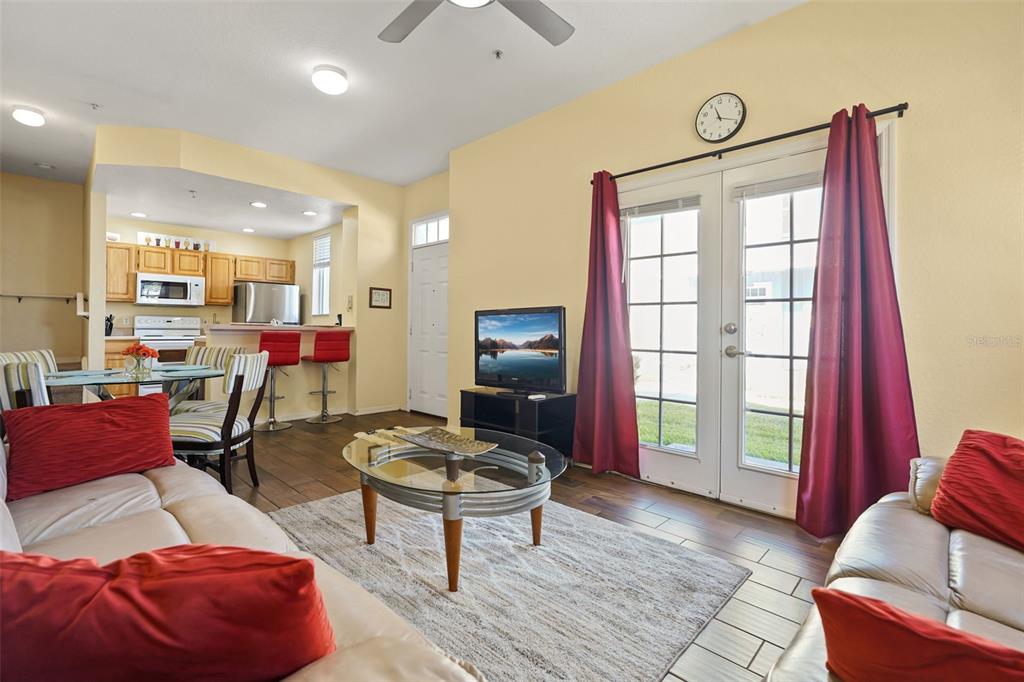 A living room with a glass coffee table, red accents, and an open kitchen area — 4021 VENETIAN BAY DRIVE UNIT 101, KISSIMMEE, FL