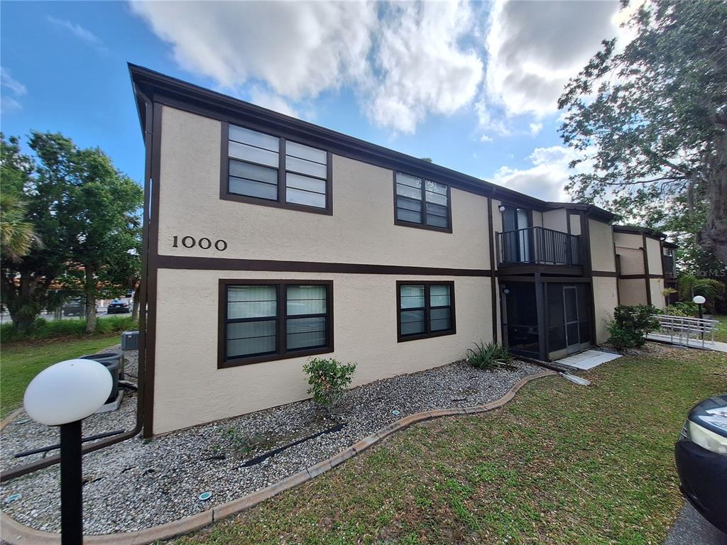 A two-story tan apartment building with dark brown trim and a screened-in balcony — 4022 BEAVER LANE UNIT 1000G, PORT CHARLOTTE, FL