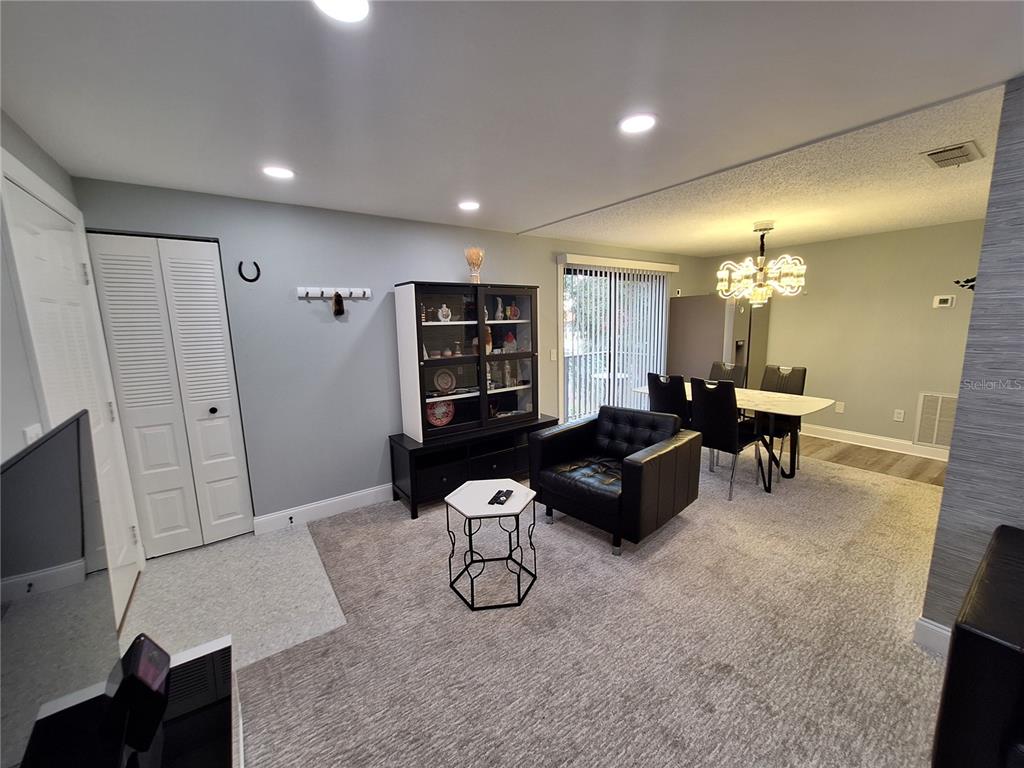 A living and dining area features gray walls, carpeted flooring, a black display cabinet, and furniture — 4022 BEAVER LANE UNIT 1000G, PORT CHARLOTTE, FL