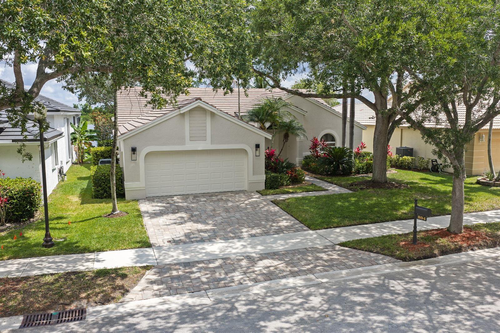 A grassy lawn leads to a large lake under a bright blue sky with clouds — 804 Heritage Drive, Weston FL 33326, WESTON, FL