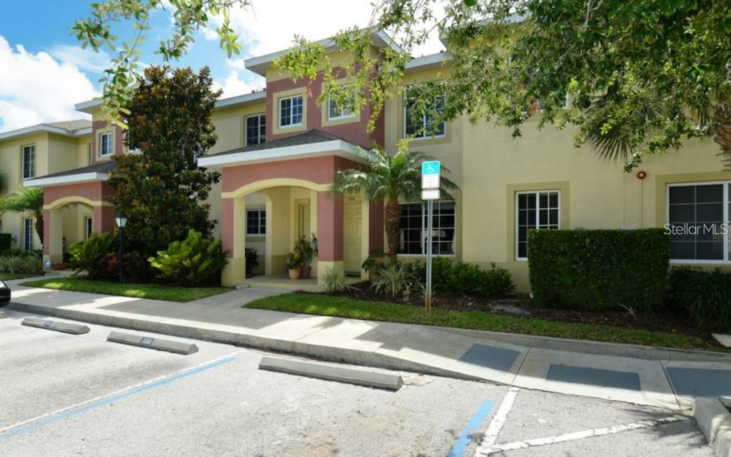 A two-story apartment building exterior with a covered entryway and a paved parking lot — 3909 45TH TERRACE W UNIT 106, BRADENTON, FL