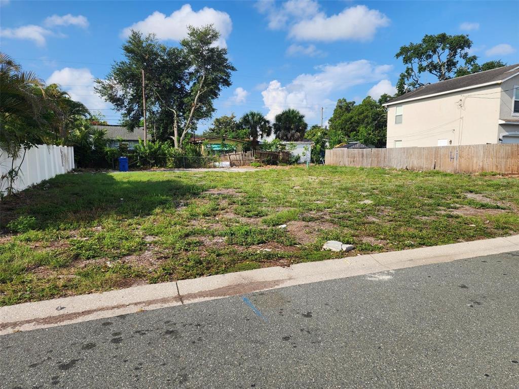 A vacant, grassy residential lot sits between two fenced properties along a paved street — 1748 31ST AVENUE N, ST PETERSBURG, FL