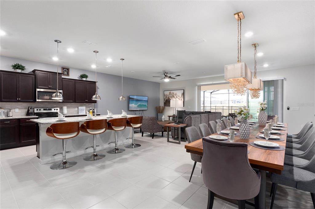 An open-concept kitchen, dining area, and living room featuring dark cabinets and tile flooring — 2316 LELANI CIRCLE, DAVENPORT, FL
