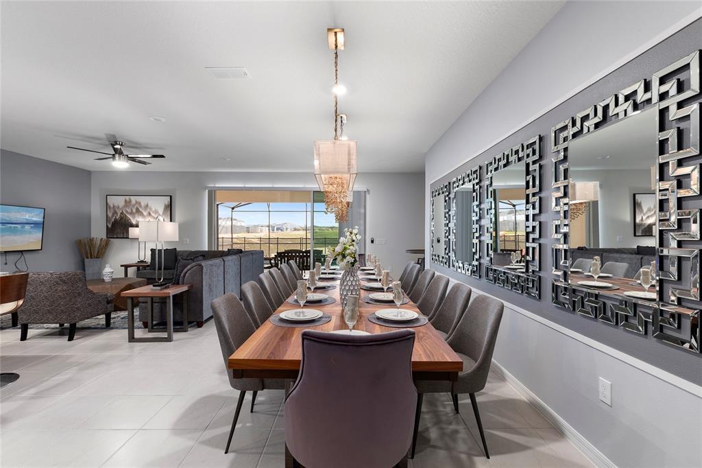 A dining room features a long wooden table, gray upholstered chairs, and decorative wall mirrors — 2316 LELANI CIRCLE, DAVENPORT, FL