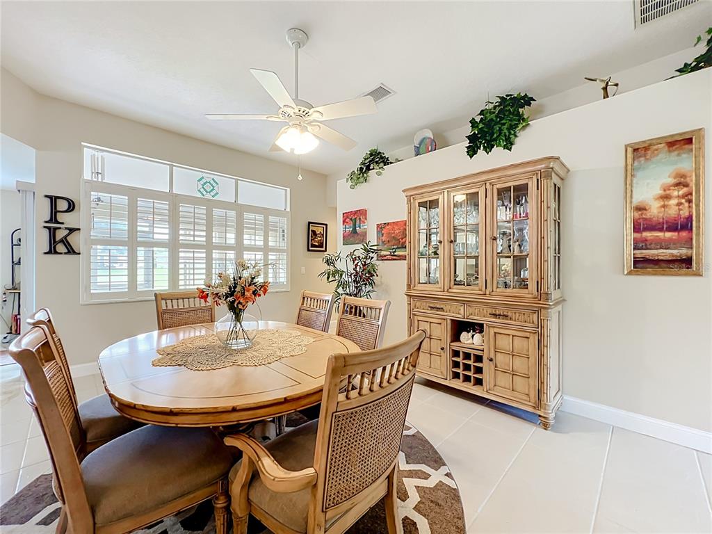 A dining room features a round wooden table, rattan chairs, and a large china cabinet — 1409 CALIFORNIA DRIVE, MELBOURNE, FL