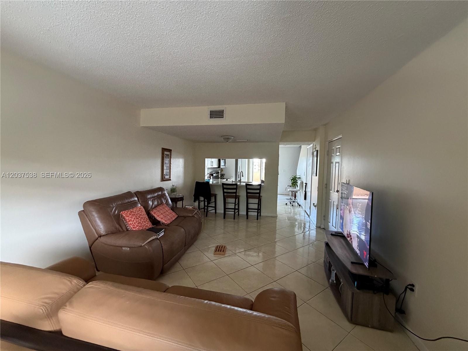 A living room features brown leather sofas, a television on a stand, and tiled floors — 14902 SW 82nd Ln # 205, Miami FL 33193, MIAMI, FL