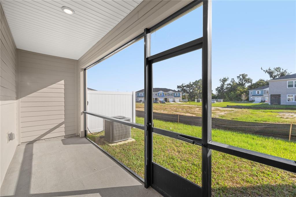 A screened-in concrete patio overlooks a grassy yard and neighboring houses under a clear sky — 3339 SE 37TH AVENUE ROAD, OCALA, FL
