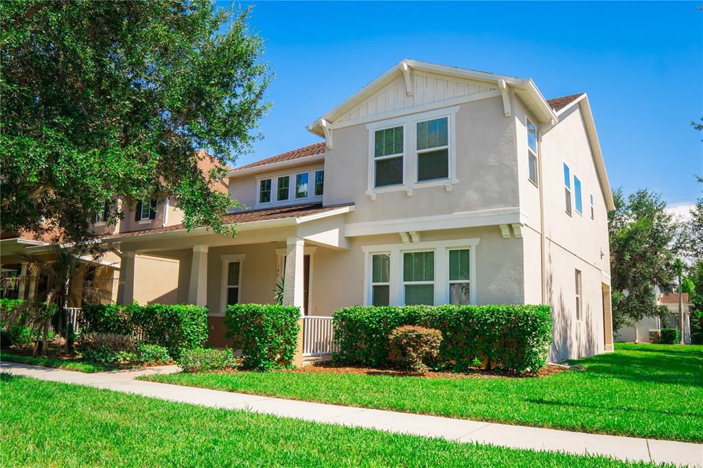 A two-story suburban house with a front porch, tan stucco siding, and a manicured lawn — 14816 PORTER RD, WINTER GARDEN, FL