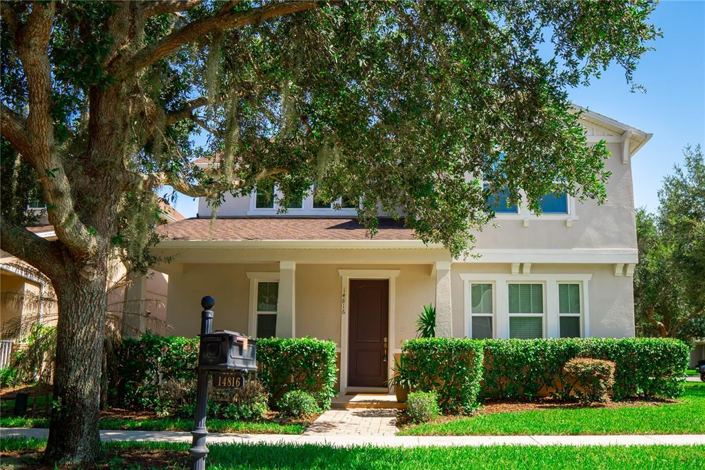 A two-story house with a brown front door, a covered porch, and a large oak tree — 14816 PORTER RD, WINTER GARDEN, FL