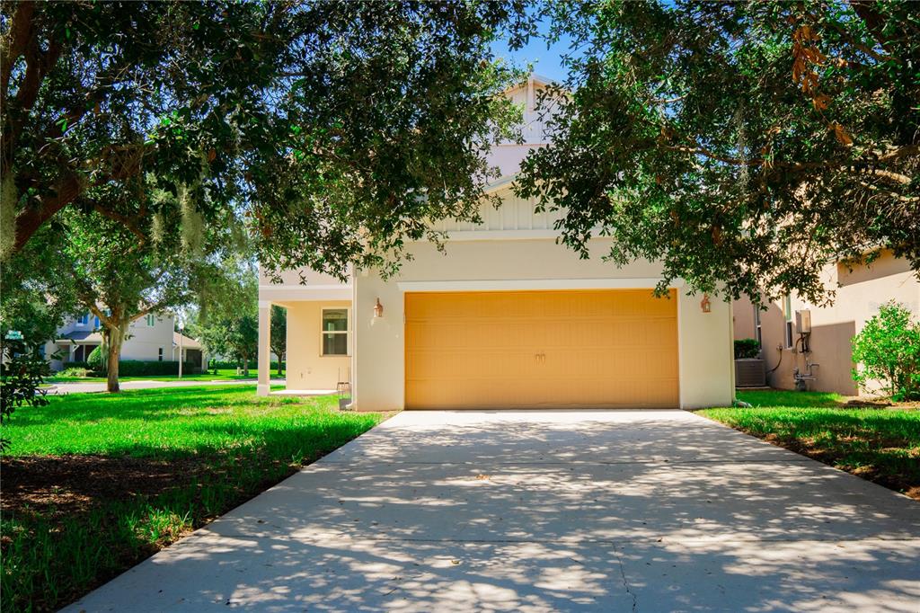 A two-story house exterior features a large yellow garage door and a concrete driveway — 14816 PORTER RD, WINTER GARDEN, FL