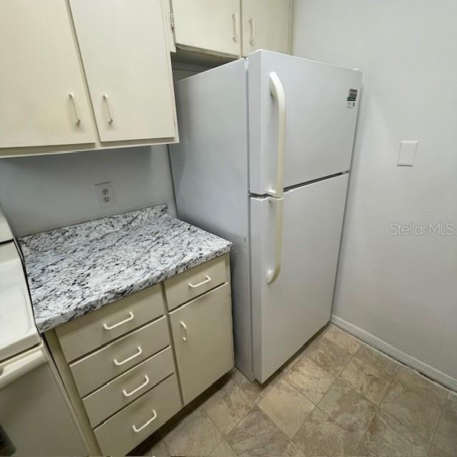 A kitchen features white cabinets, a granite-look countertop, and a white top-freezer refrigerator — 415 WYMORE ROAD UNIT 101, ALTAMONTE SPRINGS, FL