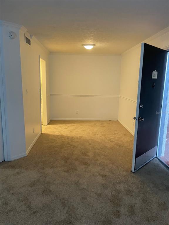 An interior view of an entryway with beige carpet, white walls, and an open door — 415 WYMORE ROAD UNIT 101, ALTAMONTE SPRINGS, FL