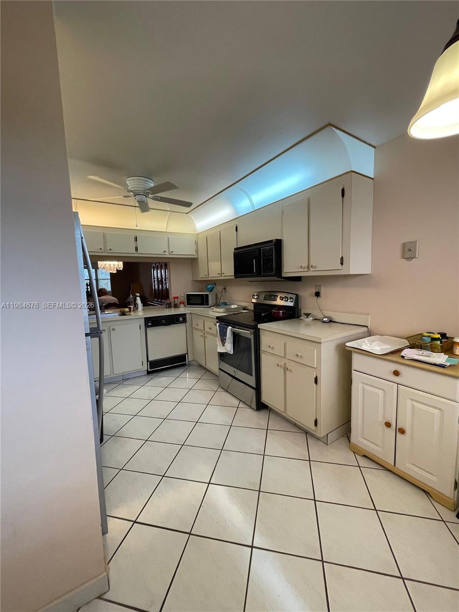 A kitchen features white cabinets, stainless steel appliances, and white tile flooring — 2606 NW 104th Ave # 301, Sunrise FL 33322, SUNRISE, FL