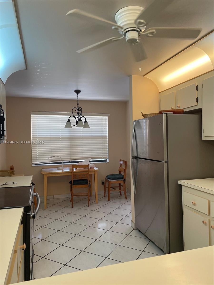 A kitchen features white cabinets, a stainless steel refrigerator, tile flooring, and a dining area — 2606 NW 104th Ave # 301, Sunrise FL 33322, SUNRISE, FL